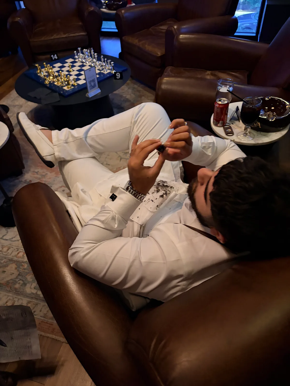 Nvar Sinclair reclined in an all-white suit with cigar ash resting on his chest — you cannot ash for the first 40 minutes